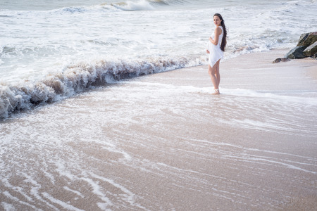Beautiful tender pregnant woman stand on the sea shoreの写真素材