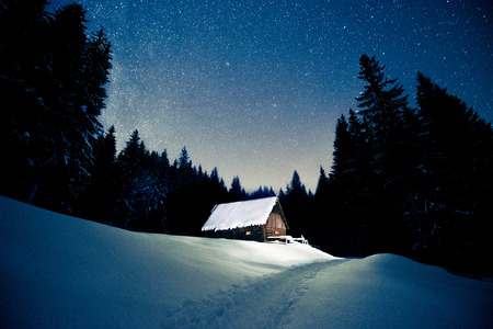 Beautiful wooden house in the winter forest under the starsの写真素材