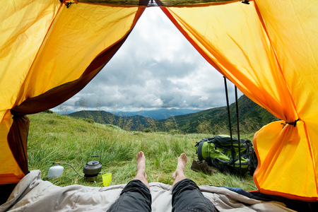 legs of the traveler in a tent with tourist equipment outdoorsの写真素材