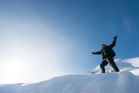 Happy climber with an ice ax in the snowy mountainsの写真素材