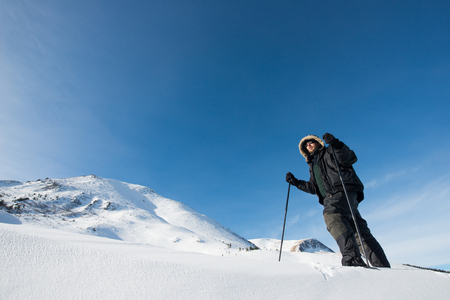 climber with trekking poles in the snowy mountainsの写真素材