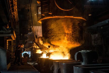 Zaporozhye / Ukraine - 07.27.2015: two steelworkers at work near the tanks with hot metal....
