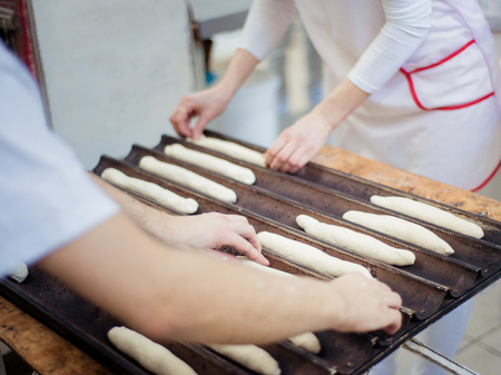 Bakers lay out the dough rolls on a baking tray