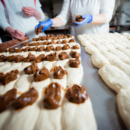 Bakers make buns from dough with filling of condensed milkの写真素材