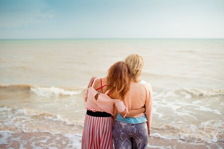 Adult daughter hugs mom on the sea shoreの写真素材