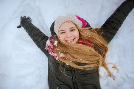 Beautiful happy girl are smiling and lying in the snow, closeup portrait.の写真素材