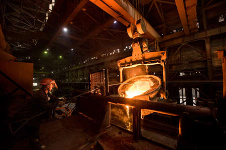 Steelworker at work near the tanks with hot metalの写真素材