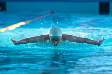 Swimmer boy swims butterfly swimming style in the pool.