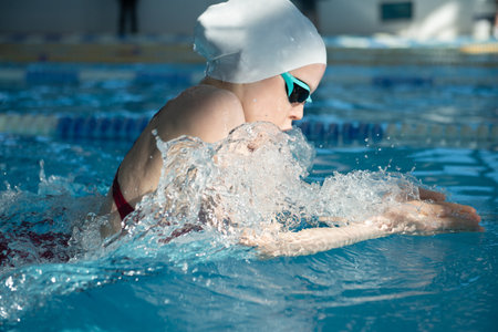 Swimmer girl swims breaststroke swimming style in the pool