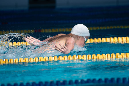 Swimmer boy swims butterfly swimming style in the pool