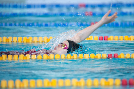 Swimmer girl swims backstroke swimming style in the pool