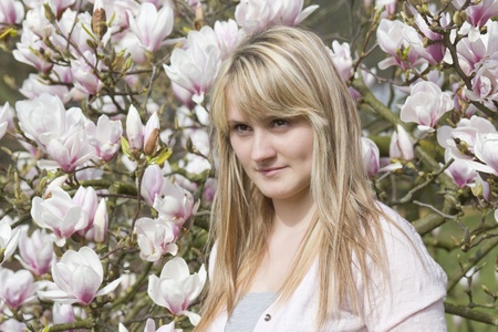 portrait of beautiful girl with blooming magnolia on background の写真素材