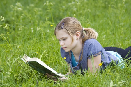 A little girl reading a book outdoor, warm spring dayの写真素材