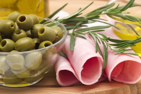 Rolled slices of ham, green olives and rosemary の写真素材