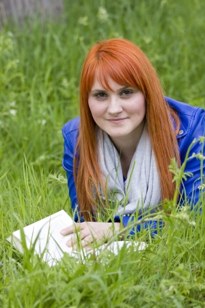 Young girl with red hair reading a book の写真素材