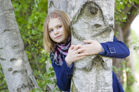 Girl hugging tree trunk and smiling の写真素材