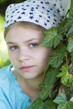 Portrait of young girl standing near tree at summer green parkの写真素材