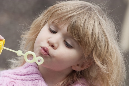 Little girl blowing soap bubblesの写真素材