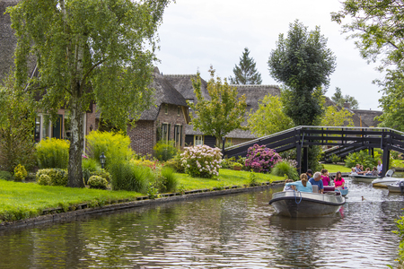 GIETHOORN, NETHERLANDS - AUGUST 01 2017: Unknown visitors in the sightseeing boating trip in a canal in Giethoorn. The beautiful houses and gardening city is know as "Venice of the North".のeditorial素材