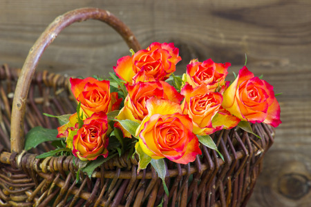 orange roses in a basket on wooden backgroundの写真素材