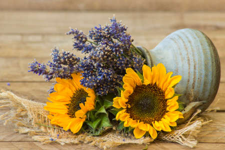 sunflowers and lavender in a vase on wooden backgroundの写真素材