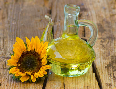 Glass bottle with sunflower oil and sunflower on wooden backgroundの写真素材