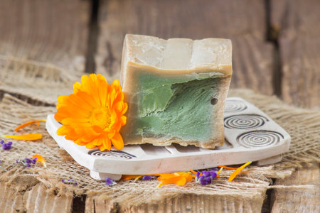 Natural handmade soap with calendula (pot marigold) on rustic wooden backgroundの写真素材