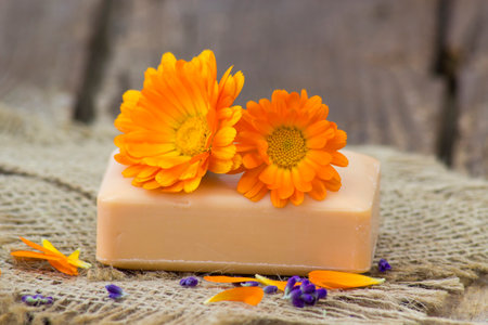 Natural handmade soap with calendula (pot marigold) on rustic wooden backgroundの写真素材