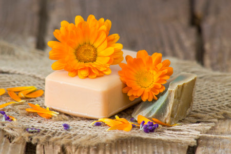 Natural handmade soap with calendula (pot marigold) on rustic wooden backgroundの写真素材