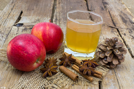 Apple juice, fresh apples, cinnamon sticks and anise stars on wooden backgroundの写真素材