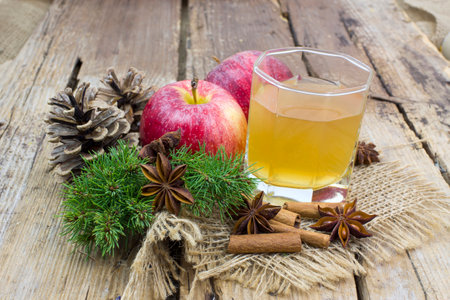 Apple juice, fresh apples, cinnamon sticks and anise stars on wooden backgroundの写真素材