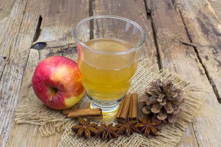 Apple juice, fresh apples, cinnamon sticks and anise stars on wooden backgroundの写真素材