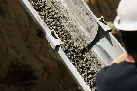 Construction worker watching over cement being pourred into new house foundation.の写真素材