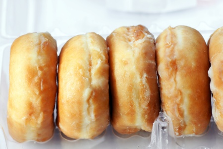 Open plastic container of sticky sugar glazed donuts or doughnuts.の写真素材