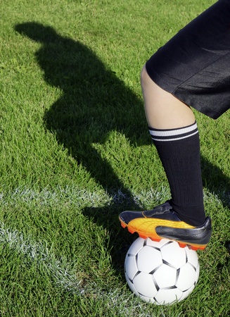 Soccer or football player waiting for the signal to kick corner ball at the corner with shadow silhouette on field grass.の写真素材