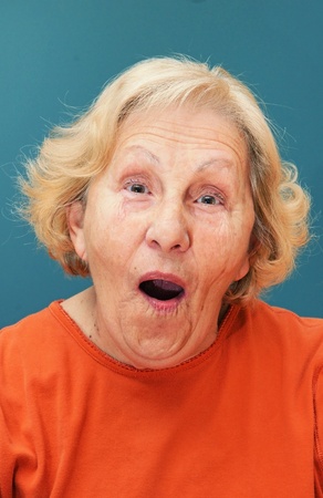 Senior woman with funny surprised look on her face with opened mouth and hint of a smile.の写真素材