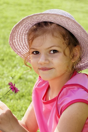 Cute little girl dressed in pink with straw hat holding a pink flower, great summer theme or youth.の写真素材