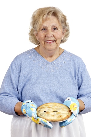 Welcome home concept: grandma is smiling while offering warm homecooked meat pie, wearing oven mits.の写真素材