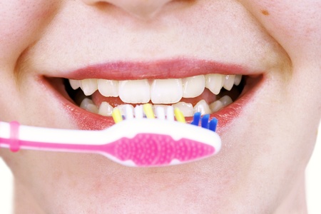 Close up of young woman perfect teeth about to clean them with pink tooth brushの写真素材