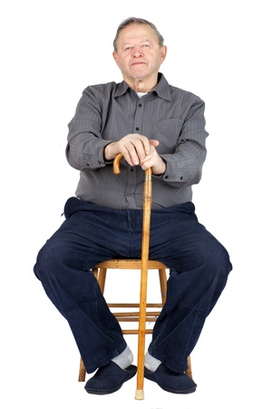 Senior or old man sitting down on old wooden chair with his cane to rest, wearing blue corduroy and slippers, isolated on white.の写真素材
