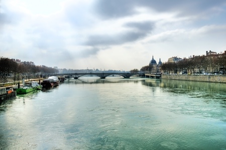 Beautiful scenery of a misty morning over the Rhone river in Lyon France with a bridge and old...