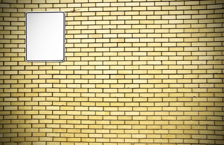 Dramatic vignette yellow brick wall background with blank white metal sign ready for your text.の写真素材