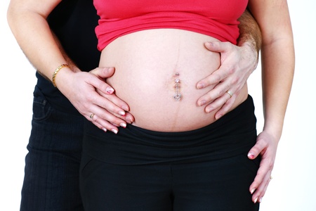 Pregnant couple, husband and wife cuddling and touching the belly, beautiful pregnancy studio shot over white.の写真素材