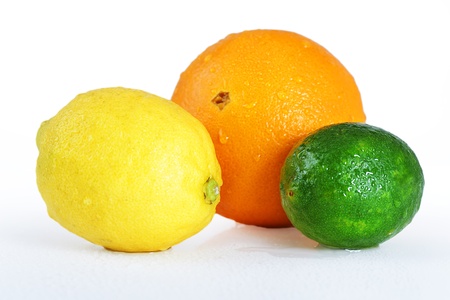 Beautiful studio still life of whole wet citrus fruits, orange, lemon and lime on white table, perfect background for nutrition, diet, healthy eating, organic or other food concept.の写真素材