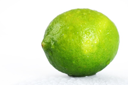 Beautiful studio shot of a fresh and wet lime, with water droplets dripping off it over white, perfect nutrition or diet background.の写真素材