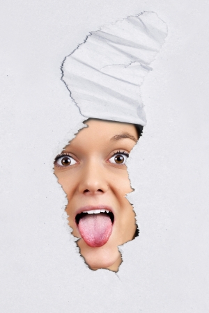 Fun ripped textured paper background with pretty young woman pulling tongue behind.の写真素材