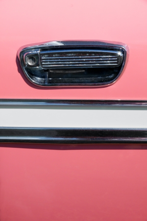 Close up on the handle and chrome decoration on an old pink vintage car; great background.の写真素材