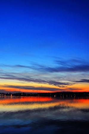 Magnificent sunset over a lake with waterfowl and city lights in a distance, dramatic HDR rendering.の写真素材