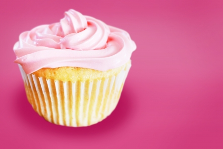 Vanilla cupcake with pink frosting over same color backgroundの写真素材
