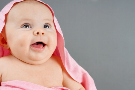 Laughing baby girl with pink blanketの写真素材